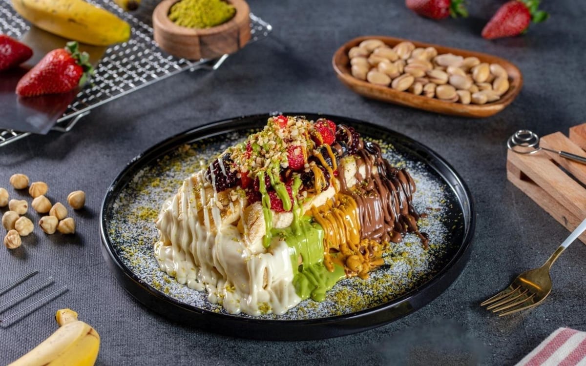 Beyaz çikolata, fıstık, karamel ve çikolata soslu; çilek, böğürtlen ve fındıkla süslenmiş waffle tabağı